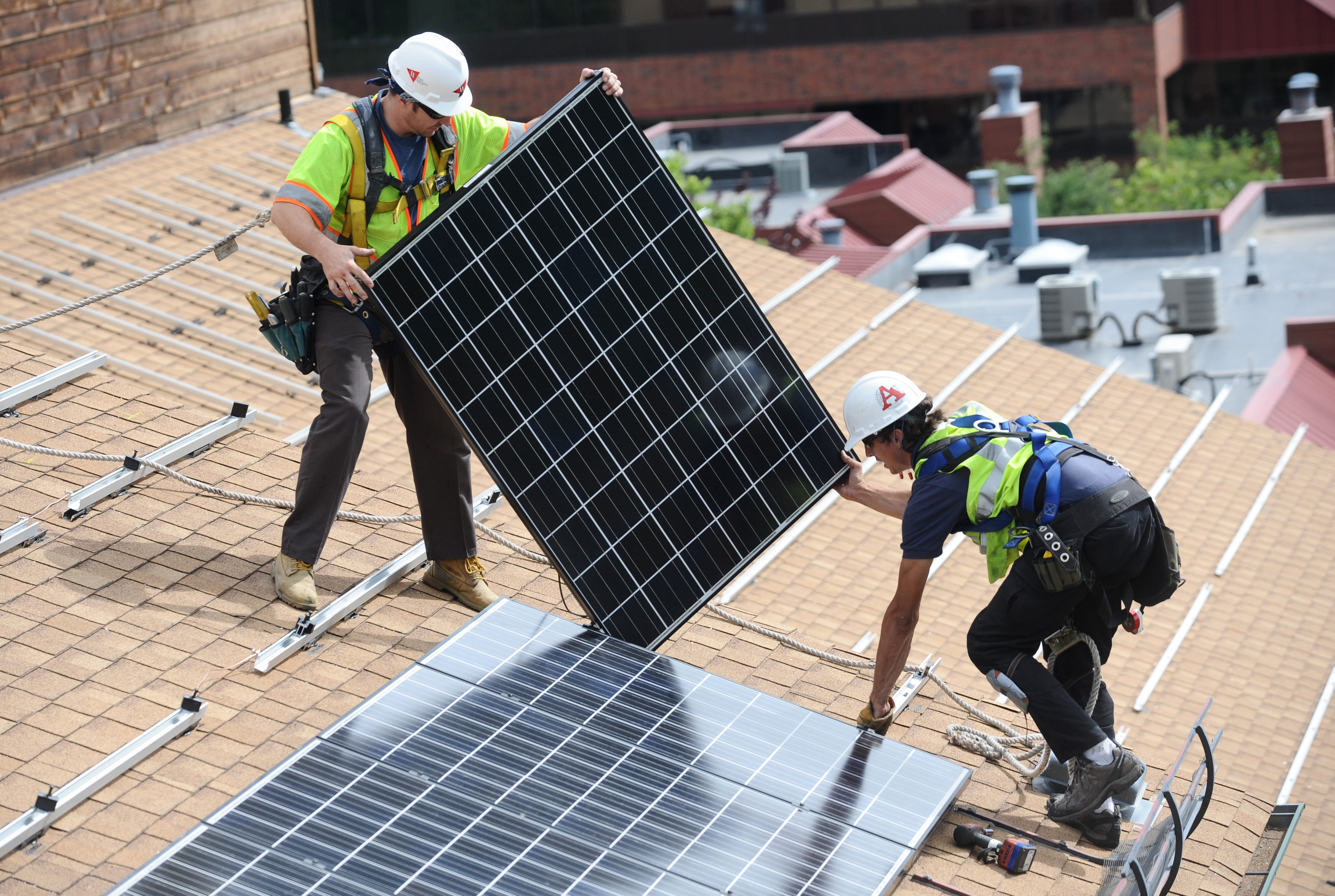خدمه پنل های خورشیدی را در یک ساختمان آپارتمان نصب می کنند.